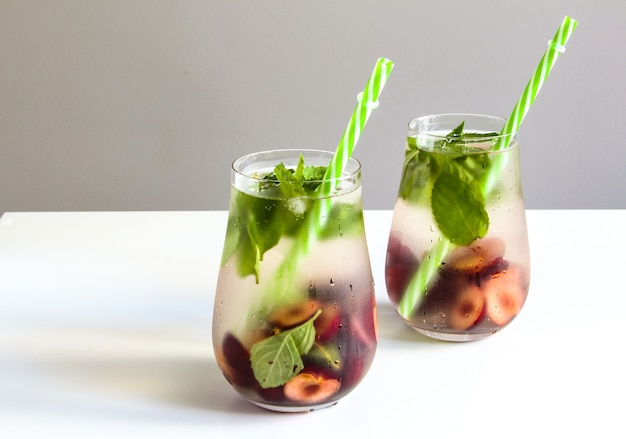 boissons froides dans de petites bouteilles cerises et limonade à la menthe cocktail mojito boisson glacée d'été