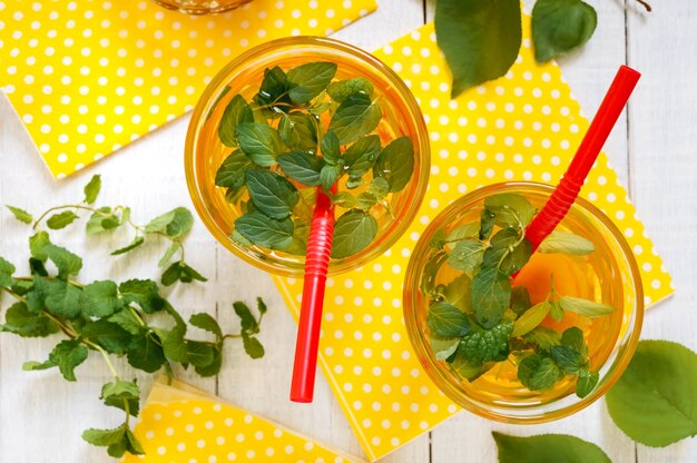 Boissons froides d'été. Délicieuse boisson rafraîchissante à l'abricot et à la menthe dans des verres sur un fond en bois blanc. Compote de fruits.