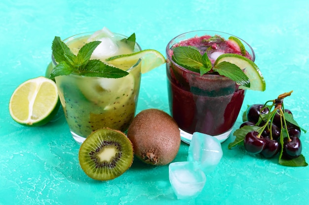 Boissons froides d'été avec fruits frais, baies et menthe. Smoothies aux cerises, cocktail de kiwi dans des verres.