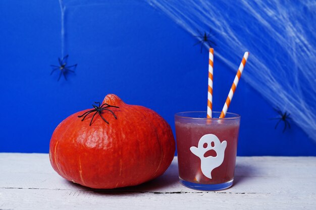 Boissons d'Halloween à la citrouille pour une fête d'enfants sur bois blanc et scène bleue avec des araignées