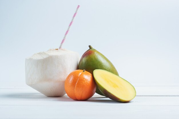 Boissons à la noix de coco avec paille, mangue et mandarine