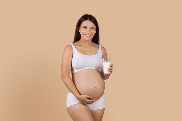 Boissons saines Femme enceinte souriante en sous-vêtements tenant un verre de lait