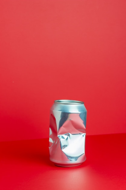 Photo boîte en aluminium froissé sur une table rouge. sans plastique. pollution environnementale. le minimalisme. conception.