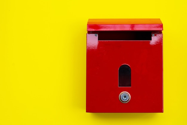 Boîte aux lettres rouge sur fond jaune.