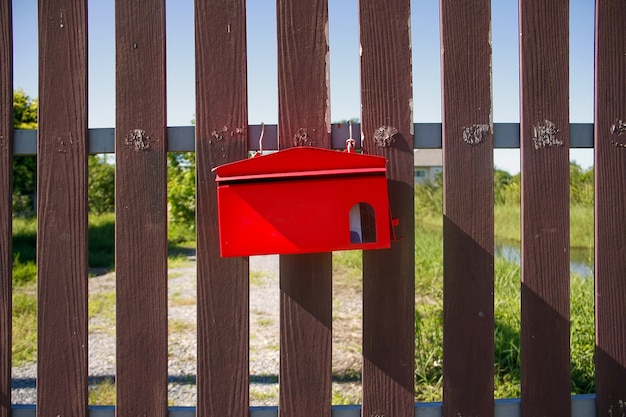 Boîte aux lettres rouge sur les portes marron devant la maison