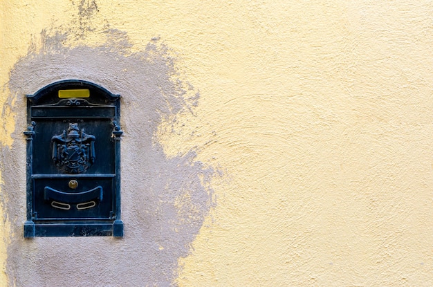 Boîte aux lettres sombre sur un mur partiellement peint