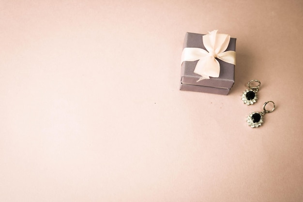 Boîte de beauté festive belle boîte cadeau avec un arc avec des boucles d'oreilles en argent avec des pierres précieuses sur un rose