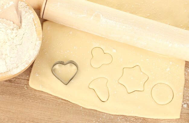 Boîte de biscuits sur la pâte roulée sur le plan rapproché de table en bois