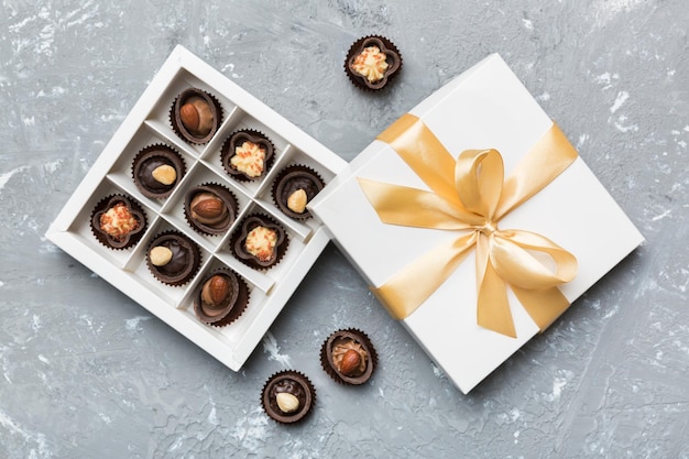 Boîte blanche avec des bonbons au chocolat et vue de dessus de ruban doré avec espace de copie