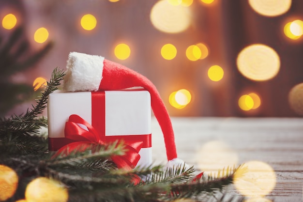 Boîte blanche de Noël ou cadeau avec ruban rouge pour le père Noël secret avec bonnet de noel sur table en bois