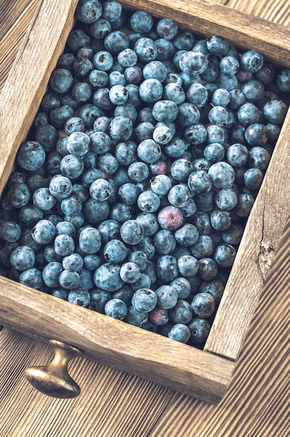 Boîte en bois de bleuets frais sur table en bois