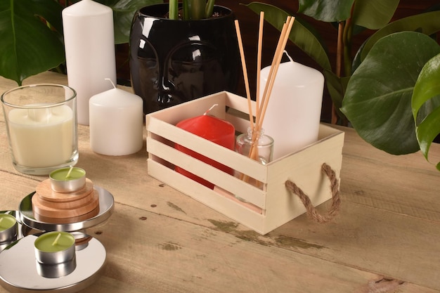 Boîte en bois avec bougies et senteurs sur une table avec fleurs et feuilles.