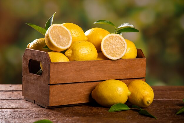 Boîte en bois avec des citrons sur fond de bois vert