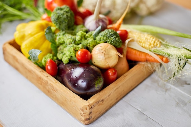 Boîte en bois avec différents légumes frais de la ferme sur fond blanc