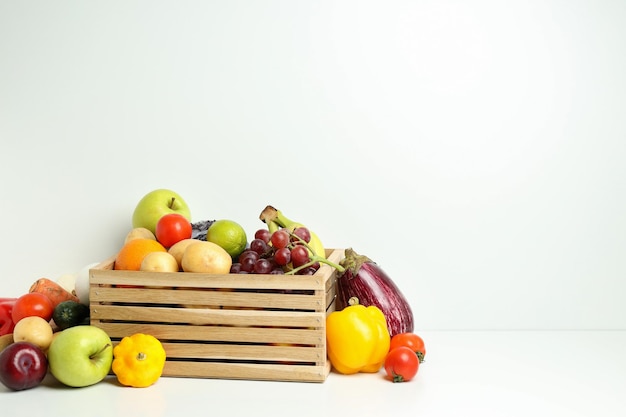 Boîte en bois avec différents légumes et fruits sur tableau blanc