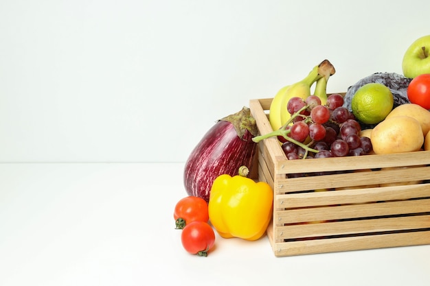 Boîte en bois avec différents légumes et fruits sur tableau blanc