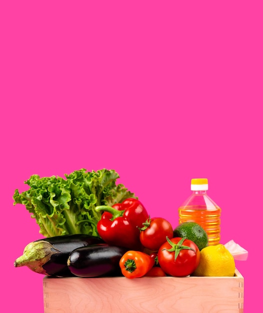 Boîte en bois avec de l'huile de tournesol de légumes frais sur fond rose Concept de livraison ou de don