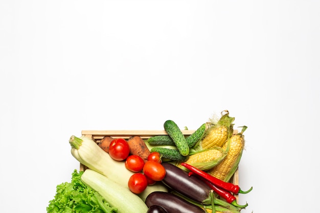 Boîte en bois avec des légumes frais sur fond blanc.