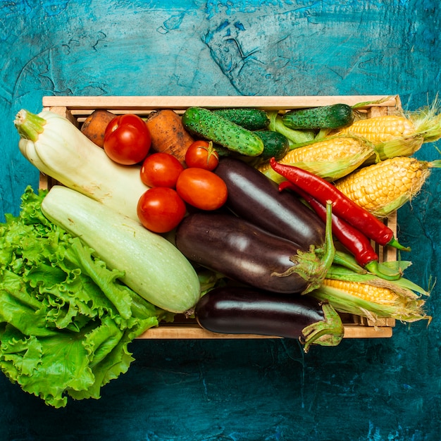 Boîte en bois avec des légumes frais sur un fond de pierre bleue. Bon concept de récolte, produit naturel. Mise à plat, vue de dessus