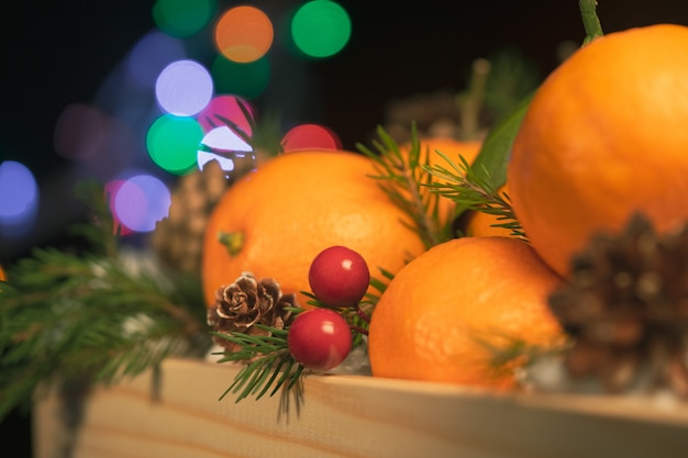 Boîte en bois avec des oranges, des branches de sapin et des pommes de pin. Noël encore la vie.