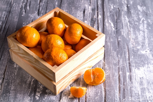 Photo boîte en bois avec des oranges fraîches de supermarché sur fond gris. vue de dessus