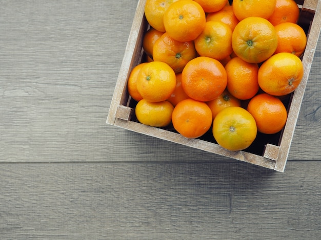 Boîte en bois remplie de mandarines. une mandarine pelée