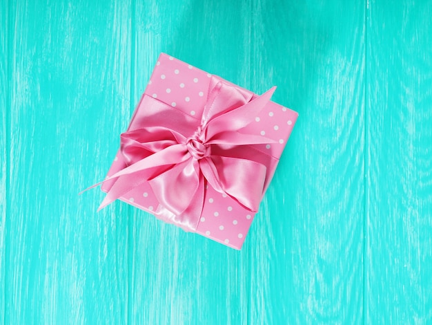 Une boîte-cadeau avec un arc rose sur un fond en bois, copie de l'espace texte.