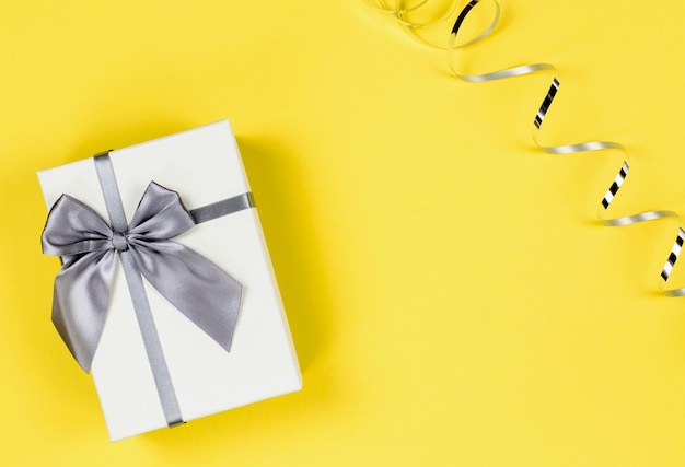 Boîte cadeau blanche et serpentine sur fond jaune Fond festif