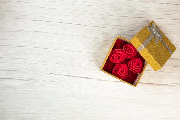 Boîte cadeau ou cadeau or avec fleur de roses dans le présent sur une table en bois blanc vue de dessus plat poser st...