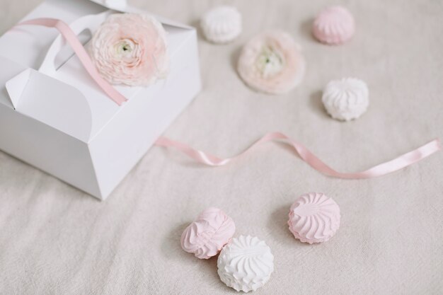 Boîte cadeau ou cadeau avec ruban rose et fleurs sur la vue de dessus de la surface blanche