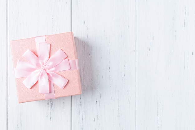 Boîte cadeau décorative rose avec noeud sur table en bois