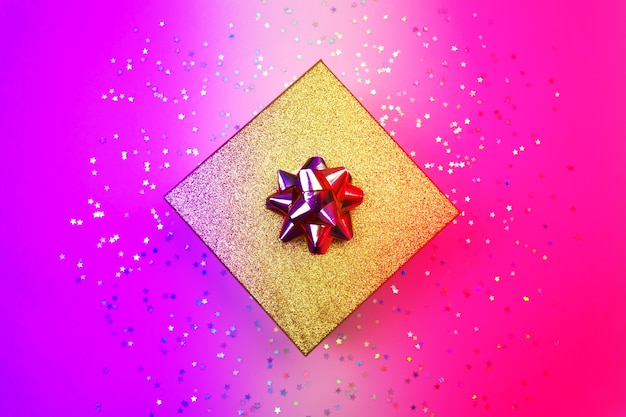 Boîte cadeau dorée avec ruban et confettis