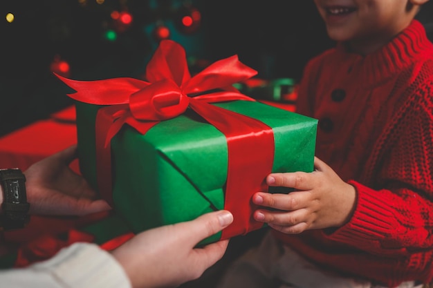 Boîte cadeau entre les mains de la mère et du fils l'humeur de Noël