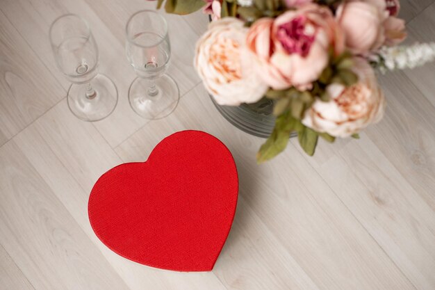 Photo une boîte-cadeau en forme de coeur rouge et un bouquet de fleurs sont au sol le jour de la saint-valentin