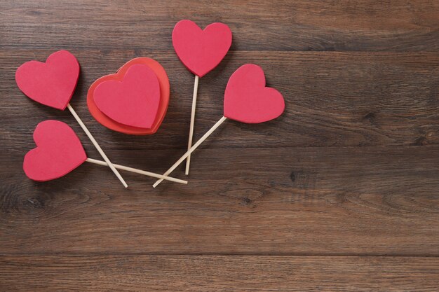 Boîte cadeau en forme de coeur rouge sur table en bois.