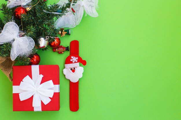 Boîte de cadeau de Noël et branches de sapin avec des jouets sur fond vert