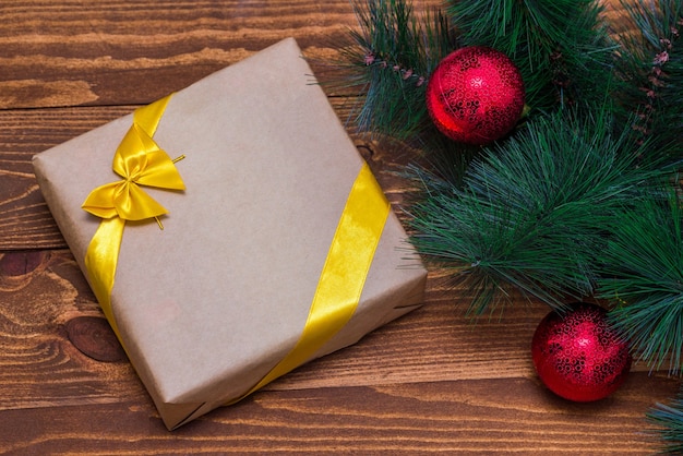 Boîte de cadeau de Noël et décor de branche d'arbre sur table en bois.