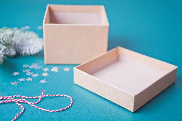 Boîte de cadeau de Noël ouverte et vide sur le bleu avec une branche de pin et des étoiles