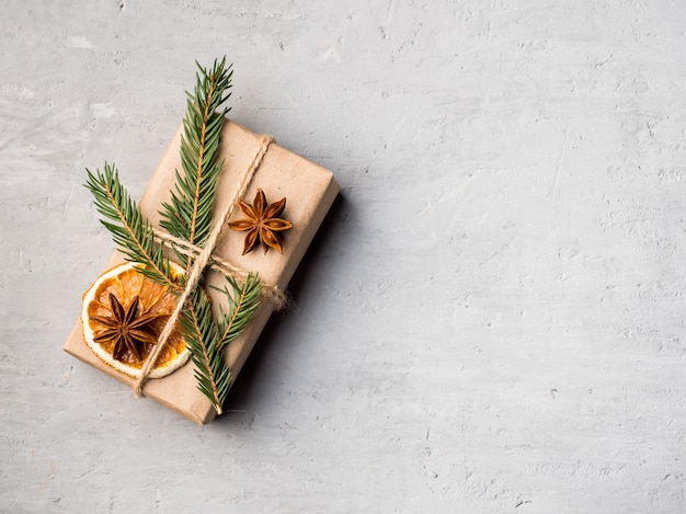 Boîte de cadeau de Noël en papier avec des épices d'hiver sur un béton gris