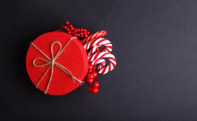 Boîte de cadeau de Noël rouge Décoration avec des cannes de bonbon sur fond noir