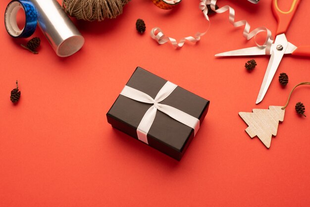 Boîte-cadeau noire dans une composition de déformation de cadeau de Noël Fond rouge vif