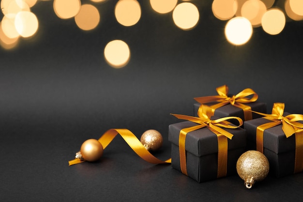 Boîte cadeau noire avec un nœud de ruban doré sur fond noir