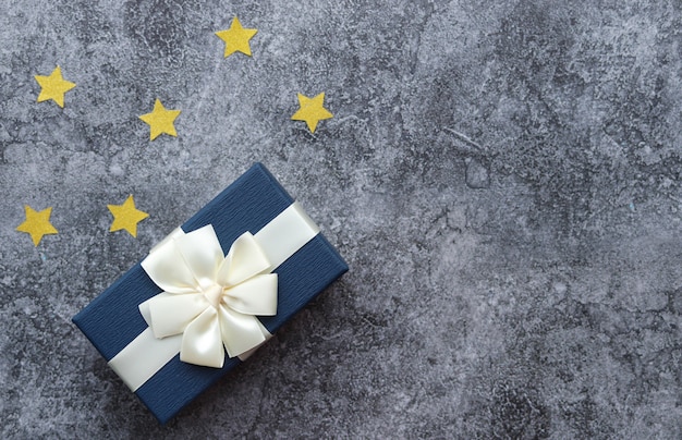 Une boîte avec un cadeau pour un homme, une surface en béton gris