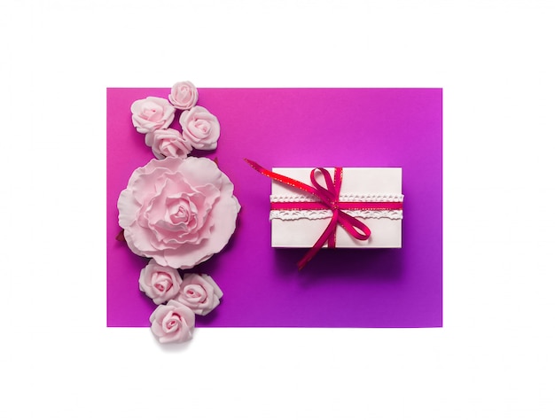 Boîte cadeau présente des décorations à plat. Ruban cadeau rose fleurs blanches vue de dessus