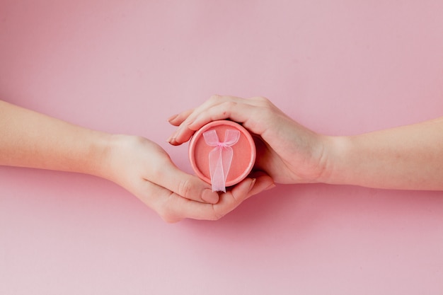 Boîte cadeau ronde rose dans les mains des femmes. Concept de fête pour la Saint Valentin, la fête des mères ou l'anniversaire