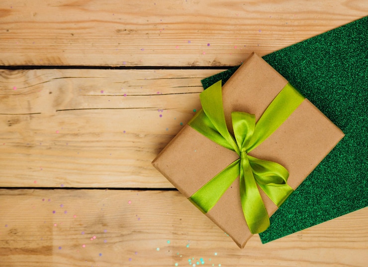 Photo une boîte-cadeau avec un ruban vert et un arc sur un fond en bois. bon concert d'anniversaire.