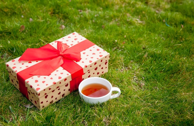 Boîte-cadeau et tasse de thé sur l'herbe verte