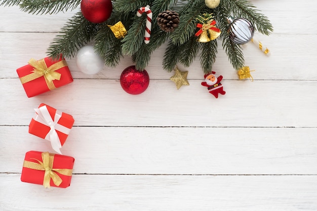 Boîte de cadeaux rouge Noël présent et feuilles de sapin avec des éléments décoratifs sur fond en bois blanc