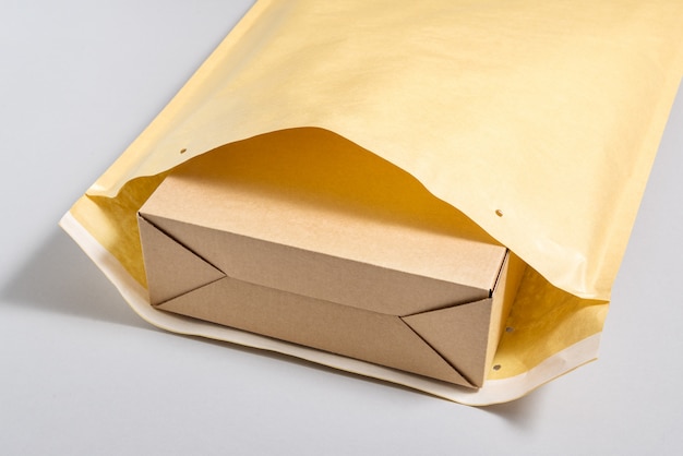 Boîte en carton brun à l'intérieur d'une grande enveloppe postale