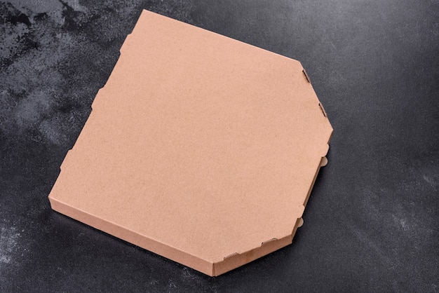 Boîte en carton marron de forme carrée pour le transport et la livraison de pizza. Cuisine méditerranéenne